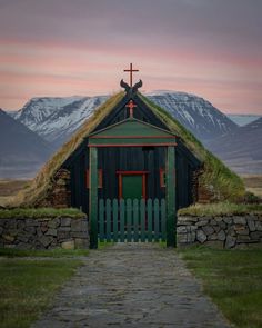 a small building with a cross on top and a green door leading to the entrance