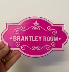 a person holding up a pink sticker with the words, branley room on it