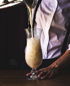 a person pouring something into a glass on top of a table