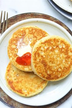 two pancakes on a plate with ketchup and butter are ready to be eaten