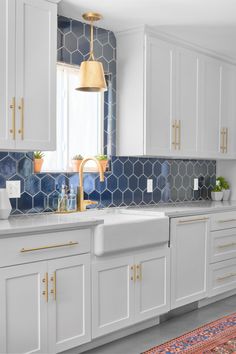 a kitchen with white cabinets and blue tiles on the backsplash, gold accents