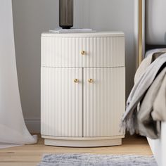 a white cabinet sitting next to a bed in a bedroom