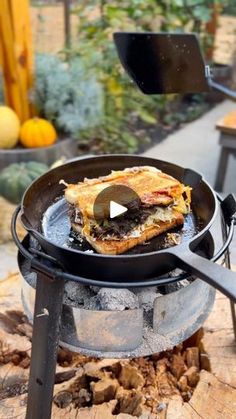 a pan with food cooking on it sitting on top of a fire pit in the middle of a yard