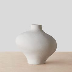 a white vase sitting on top of a wooden table