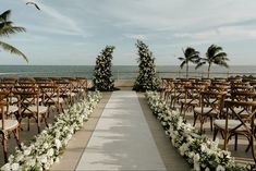 an outdoor wedding ceremony setup with chairs and flowers on the aisle, overlooking the ocean