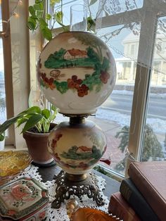 two vases sitting on top of a table next to a potted plant in front of a window