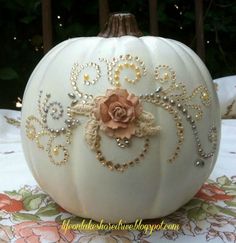 a white pumpkin decorated with beads and a rose