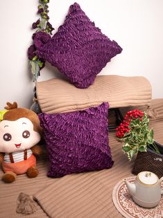 the pillows are piled on top of each other near a coffee cup and potted plant