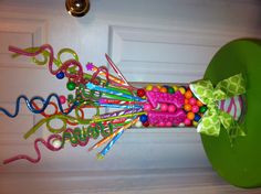 a vase filled with lots of colorful candy on top of a green table next to a door