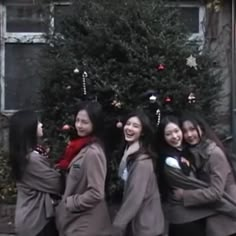 group of girls standing in front of a christmas tree with their arms around each other