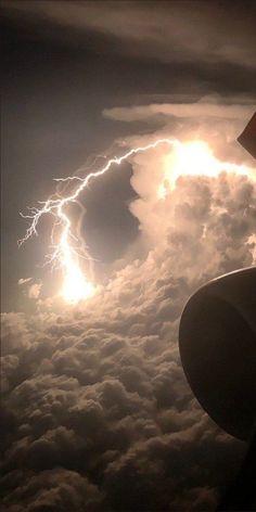 the view from an airplane window shows lightning and clouds