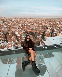 a woman sitting on top of a glass floor in front of a cityscape