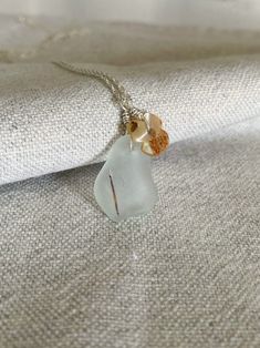 Drop pendant in authentic sea glass collected on the beach, perfectly smoothed by the sea water, white in color, with small mother-of-pearl flower-shaped pendant. The sea glass fragment has a hollow inside full, which gives the effect of a dark line. This type of sea glass fragment, in the water for several years, is not easily found, and is therefore considered rare. The pendant was hand drilled, and the hook was made from hand-worked silver wire. Pendant size: Width: 1.7cm Height: 2.3 cm glass White Minimalist Glass Jewelry, White Coastal Style Necklace For Gift, Coastal Style White Necklace For Gift, Coastal Style White Necklace As Gift, Nickel-free White Necklace For Beach, Nickel Free White Necklace For Beach, Beach Pendant Jewelry With Recycled Glass, White Glass Beach Necklace, White Glass Beach Jewelry