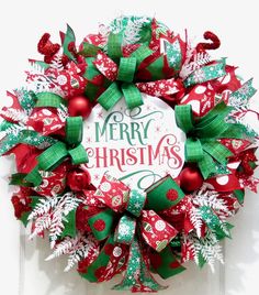 a red and green christmas wreath hanging on the front door