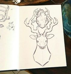 an open book with drawings of deer heads and antlers on the pages, sitting on a table