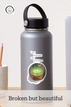 a water bottle sitting on top of a table next to a cup and pencils