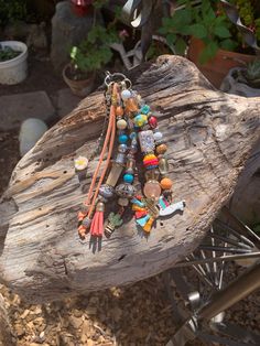 a bunch of beads that are sitting on a piece of wood in front of some plants