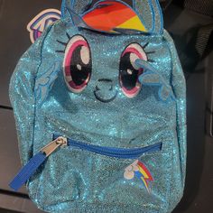 a blue backpack with sequins on it and a cat face painted on the front