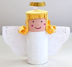 a toilet paper roll angel with a gold crown on its head and wings, sitting on a white surface