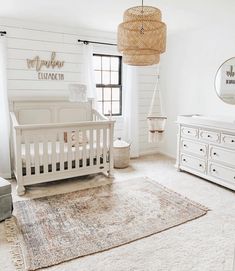 a baby's room with white furniture and rugs on the floor, including a crib