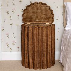 a wicker storage basket sitting on top of a bed next to a wallpapered wall