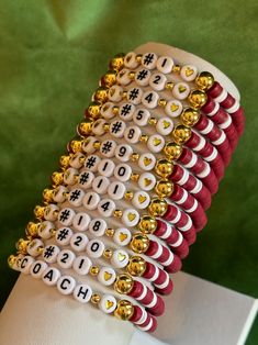 a stack of red and white bracelets with gold numbers on them sitting on top of a table