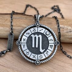 the zodiac sign is displayed on an antique style pendant with black and silver accents, along with other astro symbols