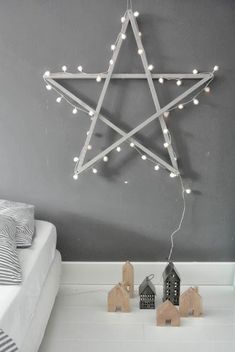 a white bed sitting next to a star light on top of a wooden block in front of a gray wall