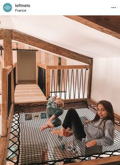 two women and a baby are sitting on the floor in a loft with exposed rafters