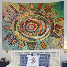 a large tapestry hanging on the wall above a bed in a room with a white headboard