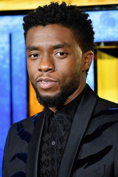 a close up of a person in a suit and tie with a blue sign behind him