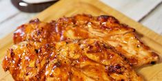 two pieces of chicken sitting on top of a wooden cutting board