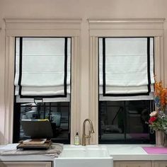 a kitchen with two windows and a sink in front of the window is decorated with flowers