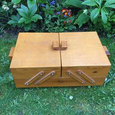 an old wooden box sitting on the ground in front of some plants and flowers,