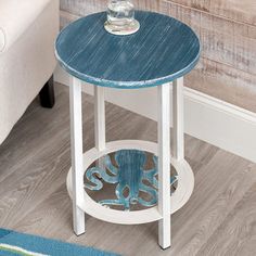 a blue and white side table with an octopus design on the bottom, sitting in front of a couch