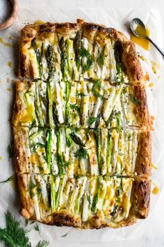 asparagus and cheese quiche on parchment paper with serving utensils next to it