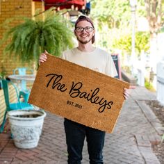 a man holding up a door mat that says the baileys st paul, mn