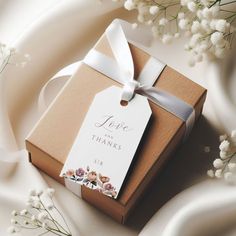 a small gift box with a white ribbon tied around it and some baby's breath flowers