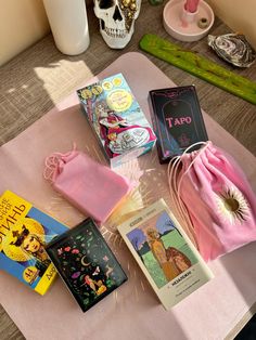 various books and other items on a pink table cloth with a skull in the background