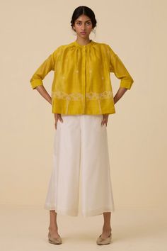 An exquisite top crafted from handwoven chanderi. Finely hand embroidered in our studio. Slim band collar and concealed placket. Delicate gathering around the neckline. 3/4 length sleeves. Two-button fastening cuff. Slip included.Note: Slight differences in embroidery speak to the hand processes involved. Garment Measurements in Inches : XS S M L XL Bust 47 49 51 53 55 Hip 56 58 60 62 64 Length 24.5 24.75 25 25.25 25.5 Flared Top, House Studio, Top Crafts, Band Collar, Signature Print, Denim Outfit, Embroidered Top, Summer House, Jacket Tops