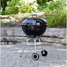 a black barbecue grill sitting on top of a brick patio