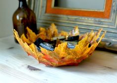 an autumn leaf bowl is sitting on a table next to some bottles and a glass bottle