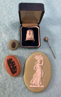 a statue of liberty is in a box next to some buttons and a ring on a blue surface