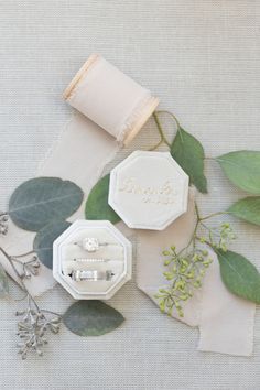 an assortment of wedding rings and greenery laid out on top of a piece of paper