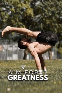 a man doing a handstand on the grass with trees in the back ground