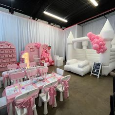 a room filled with lots of tables and chairs covered in pink balloon decorations on top of them