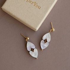 Get ready to wear your heart on your ears with our Love Earrings - a delightful symbol of love and affection! These artistic earrings are designed, laser cut, and lovingly handcrafted right here in the heart of Brighton. We've put extra care into making them lightweight and comfy, so you can wear them with ease all day long. These White Marble Heart Earrings are made with the finest acrylic and FSC certified wood. The nickel-free gold plated earring posts add an extra dash of elegance, making these heart drop earrings the perfect accessory to express your love and pride. With a drop of 4cm, these earrings strike the perfect balance between trendy and chic. They're just what you need to add a touch of love and style to any outfit, whether you're attending a special event or simply spreading Colourful Earrings, Artistic Earrings, Love Earrings, Love And Pride, Heart Drop Earrings, Earring Posts, Colorful Earrings, Gold Logo, Brass Jewelry