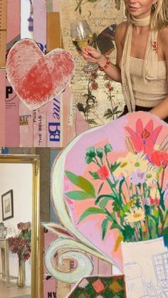 a woman holding a wine glass in her right hand while standing next to art pieces