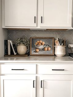 a kitchen with white cupboards and countertops has an image of apples in a bowl