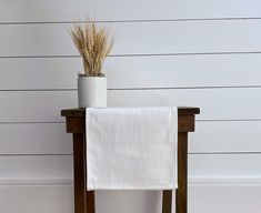 a wooden chair with a white towel on it and a potted plant next to it